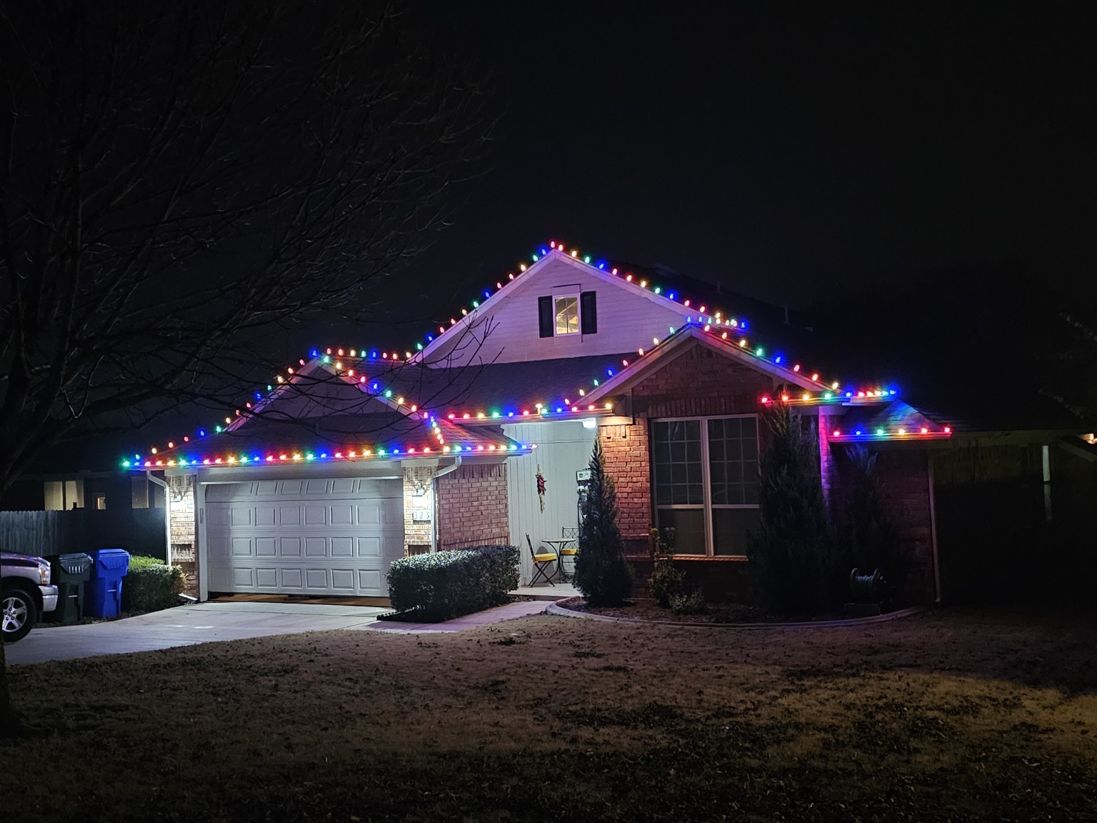 Multicolor Christmas lights following a brick home's roofline